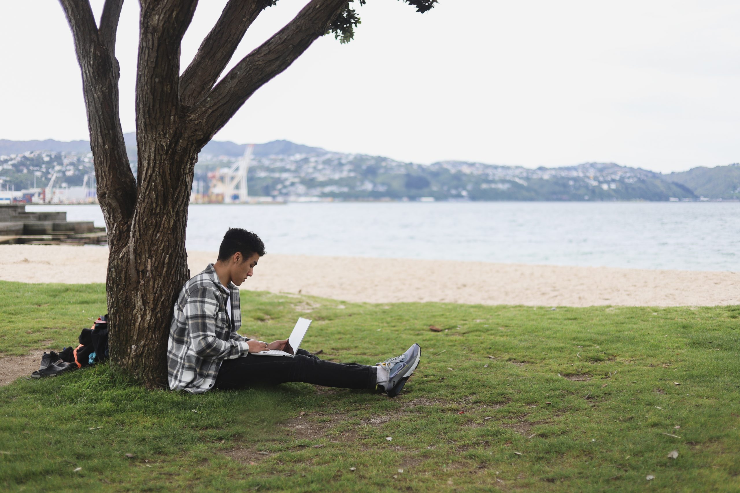 a boy studying on a completer in a park